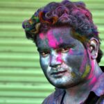 Close-up portrait of a man with colorful powders on face during Holi festival in Lucknow, India.